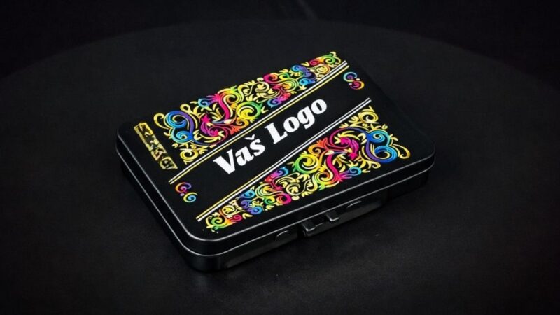 Metalna kutija sa dekorativnim motivima i natpisom Vas logo na crnoj pozadini